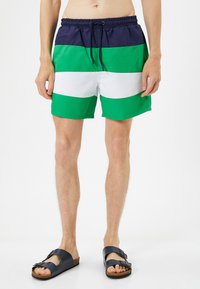 Bañadores coloridos con rayas horizontales en azul marino, verde y blanco. Hechos de material de secado rápido, con una cintura elástica y cordón ajustable.