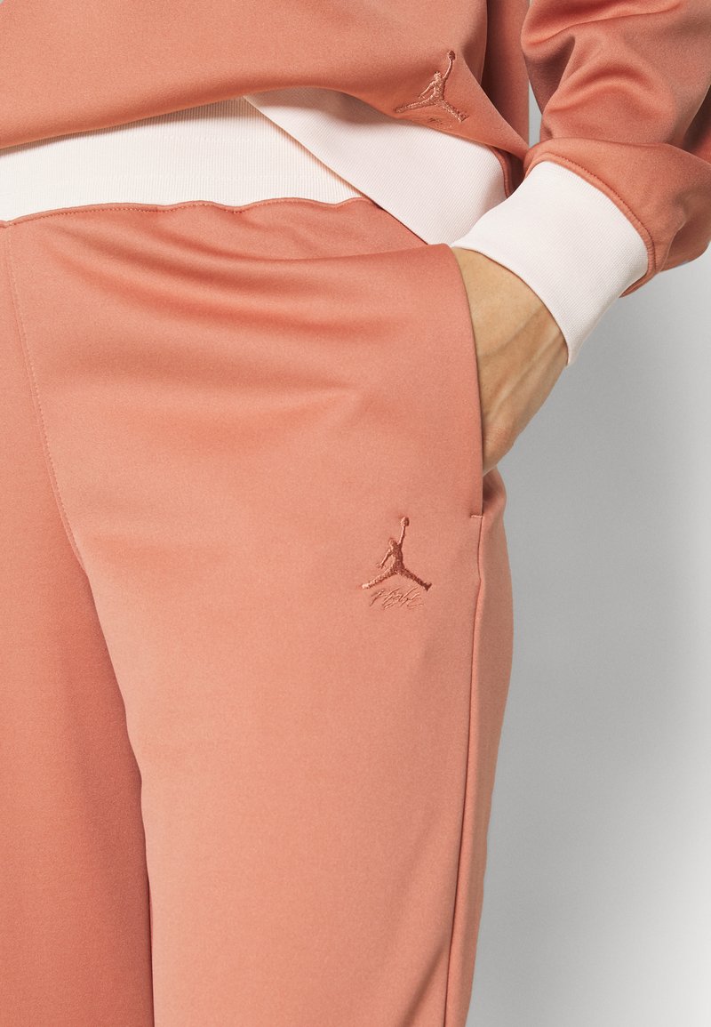 Pantalons de sport légers en rose, avec une texture douce, arborant un logo Jumpman brodé et une taille contrastante blanche.