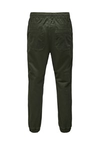 Donker groene broeken met een elastische tailleband, voorzien van twee achterzakken, taps toelopende pijpen en elastische boorden bij de enkels. Glad textuur van de stof.