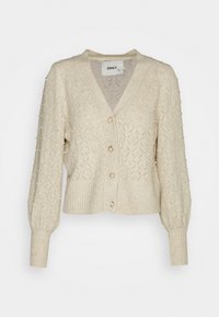 Beżowy sweter z dzianiny z wzorem w diamenty, perłowymi zdobieniami, dekoltem w serek i ściąganym dołem z zapięciem na guziki. Długie, bufiaste rękawy.