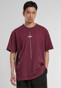 Burgundy cotton t-shirt featuring a crew neck and short sleeves. It has a white printed text design centered vertically.