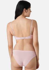 Reggiseno rosa chiaro e slip coordinato, dotati di spalline regolabili e chiusura con gancio e asola sul retro, con una texture liscia e morbida.