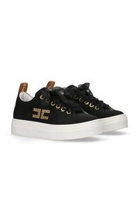 Sneaker nere in tela con suola piatta bianca, accessori in oro e lacci in nastro nero. Presentano un logo decorativo in strass.