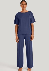 Marineblauw loungewear set met een T-shirt met korte mouwen en een brede halsopening, en losse rechtvallende broek. Zachte stof, minimalistisch ontwerp.