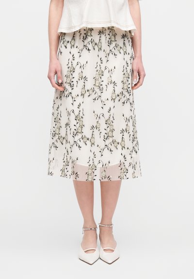Μίντι φλοράλ φούστα σε κρέμ απόχρωση με κάθετες ρίγες, διακοσμημένη με πράσινα και μπεζ κεντητά λουλούδια, με τελείωμα από διαφανές ύφασμα.