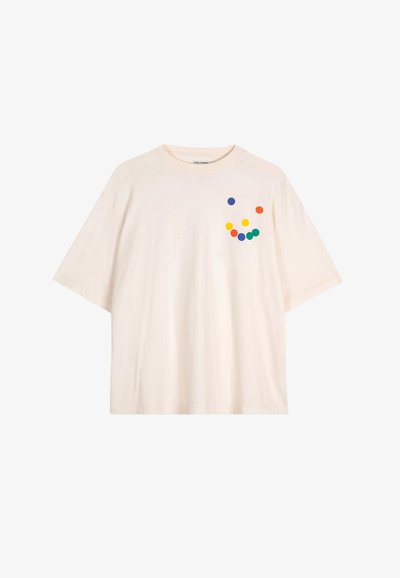 Camiseta de algodón de color crema, de gran tamaño, con mangas cortas y un patrón de puntos colorido en naranja, amarillo, verde y azul.