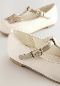 Helle rosa Stoff-Mary-Jane-Schuhe mit einer silbernen Schnalle, verziert mit einer glitzernden Schleife an der Vorderseite, flacher Sohle und glatter Textur.