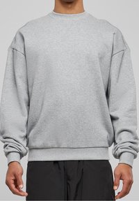 Sudadera de algodón gris con mangas largas, cuello redondo acanalado y puños. Presenta un diseño de hombros caídos y un corte relajado.