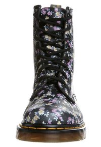 Blommig snörad känga med svart syntetöverdel och små lila, gula och vita blommönster, samt en tjock, strukturerad gummisula.