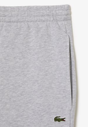 Hellgraue Jogginghose mit elastischem Bund, Seitentasche und kleinem grünen Krokodil-Logo nahe am Saum.