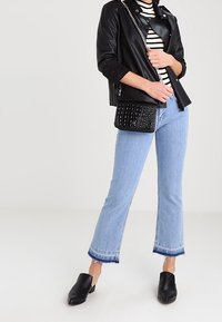 Svart läderbikerjacka, randig skjorta, ljusblå kort denimjeans med fransad nederkant, och svarta slip-on mules. Texturerad handväska med kedja.