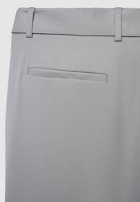 Helle graue Stoffhose, Rückansicht, die Gürtelschlaufen und eine einzelne horizontale Paspeltasche über dem Gesäß zeigt.
