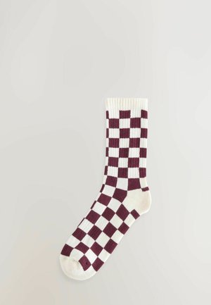 Bordovo-krémové kárované ponožky s rebrovým manžetom. Obsahujú pletený vzor s alternujúcimi štvorcami. Mäkká textúra látky.