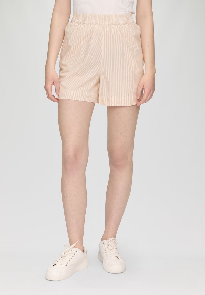 Helle rosa, gestreifte Shorts mit einem elastischen Bund. Aus weichem Material gefertigt. Kombiniert mit weißen Sportschuhen vor einem schlichten Hintergrund.