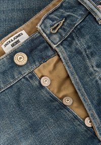 Τζιν παντελόνια σε σκούρο μπλε με ταμπά εσωτερική επένδυση, με μεταλλικά κουμπιά και υφασμένη ετικέτα που γράφει «JACK & JONES ARCHIVE».