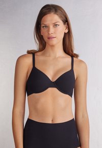 Svart BH med justerbara band, sömlösa kupor och en jämn textur. Har en klassisk design med en diskret stil.