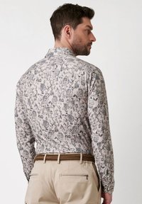 Langekleedhemd in lichtbeige met een ingewikkeld grijs bloemenmotief, met button-down kraag en gestructureerde stof. Achteraanzicht toont een getailleerde pasvorm.