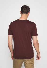 Bordeaux kortärmad t-shirt med klassisk rund hals och mjuk textur, med en enkel design utan ytterligare accenter.