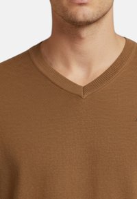 Maglione marrone a scollo a V realizzato in tessuto lavorato a maglia testurizzato con bordi a costine. Presenta un logo discreto sul lato sinistro del petto.
