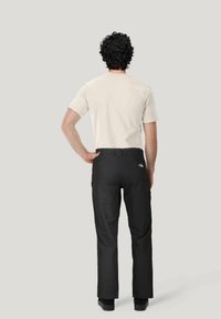 Zwarte broek met een rechte snit, voorzien van een tailleband en achterzakken, gecombineerd met een lichtgekleurde overhemd met korte mouwen.