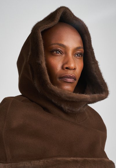 Poncho marrone con cappuccio, caratterizzato da morbida rifinitura in pelliccia, texture liscia e vestibilità ampia, progettato per calore e copertura.