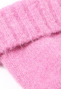 Material tricotat de culoare roz, cu o textură moale și pufoasă. Prezintă o margine pliată și un model dens, cu nervuri, în care sunt împletite fire roz deschis și roz închis.