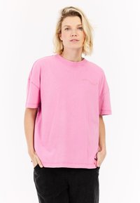 Korte mouwen, relaxed-fit t-shirt in roze katoen. Heeft een ronde hals en subtiele borduursels aan de voorkant. De textuur lijkt glad en zacht.