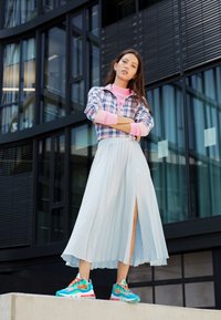 Rutigt button-up skjorta i blå/rosa, ljusblå plisserad midikjol med sidoklyfta, och flerfärgade sneakers med överdriven sula.