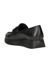 Scarpa slip-on in pelle nera con punta arrotondata, tacco a zeppa basso e suola testurizzata. Presenta una fascia decorativa e dettagli di cucitura minimali.