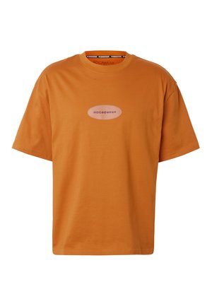 T-shirt orange à manches courtes avec col rond, présentant un petit logo ovale portant l'inscription "ROCAWEAR" centré sur la poitrine.