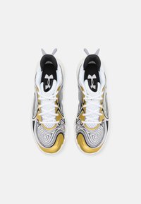 Sportieve schoenen met een witte mesh bovenkant, zwarte accenten, gouden details en een golvend patroon. Voorzien van veters en een gestructureerde zool.