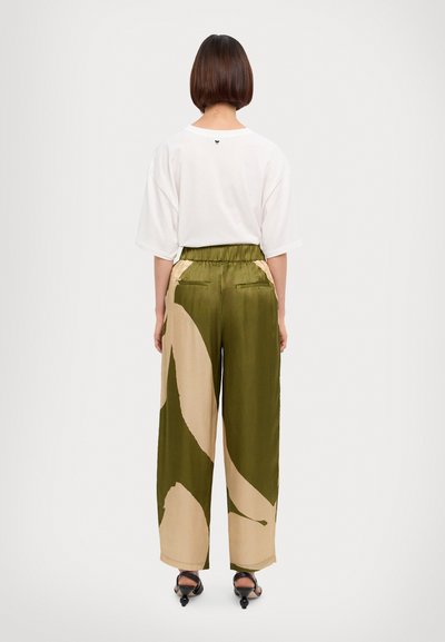 Camiseta blanca de gran tamaño con cuello redondo, combinada con pantalones de pierna ancha de patrones verde y beige. Tejido suave con cintura elástica.