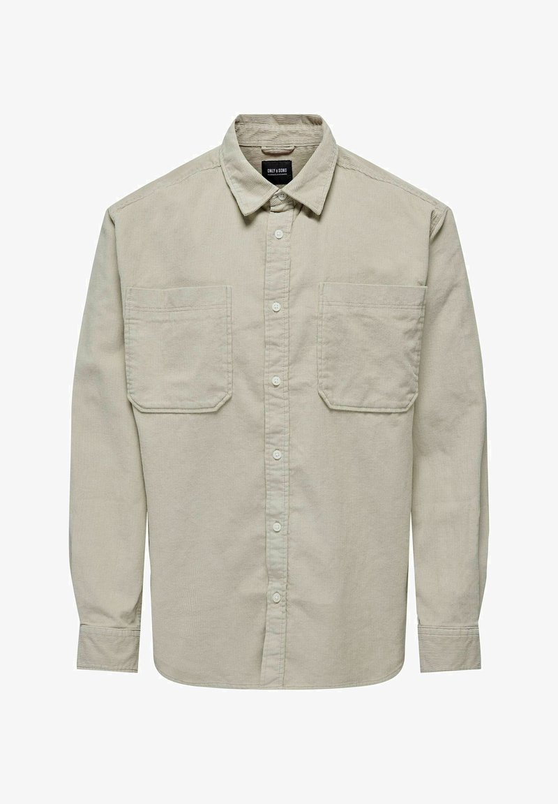 Chemise à manches longues en velours côtelé beige clair, avec un col boutonné, deux poches frontales et un ourlet légèrement arrondi.