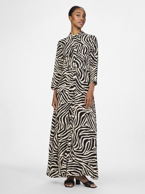 Robe maxi avec un imprimé zèbre noir et beige, manches longues, patte de boutonnage sur le devant et coupe décontractée, associée à des sandales à talons blocs noires.