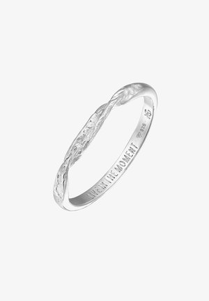 Srebrn prstan s teksturiranim, zasukanim oblikom, ki ima vrezano napis "ŽIVI V TRENUTKU" na notranji strani.