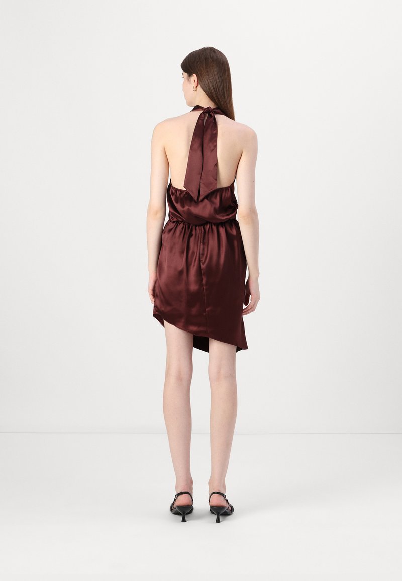 Tylny widok na bezrękawową sukienkę z głębokiego burgundu z satyny, z dekoltem halter i wiązaną kokardą, z asymetrycznym hemem.