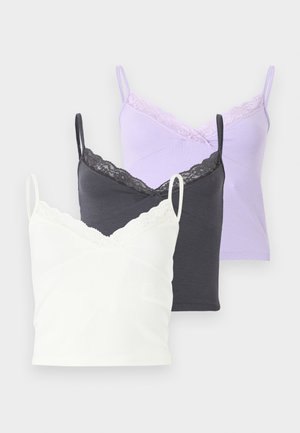 Trois camisoles pour femmes en blanc, gris foncé et lavande, chacune avec un galon en dentelle et de fines bretelles, présentées superposées sur un fond uni.