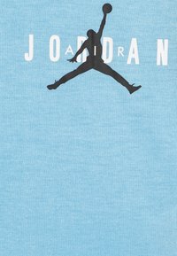 Svetlo modra bombažna majica z velikim črnim Jumpman logotipom in besedo "JORDAN" v beli barvi. Mehka tekstura, sproščen dizajn.