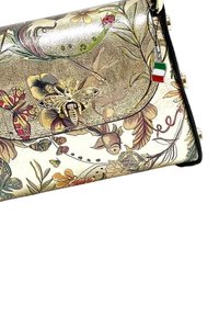 Clutch tas met bloemen- en vlinderprint, gouden metallic klep, bij-vormige sluiting en een klein label van de Italiaanse vlag bevestigd aan de rits.