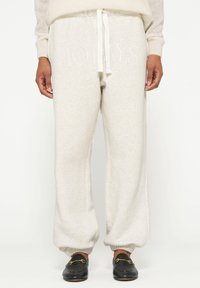 Lichtgrijze sweatpants met elastische boorden en een trekkoord in de taille, met de tekst "10 DAGEN" in een muted tint aan de voorkant.