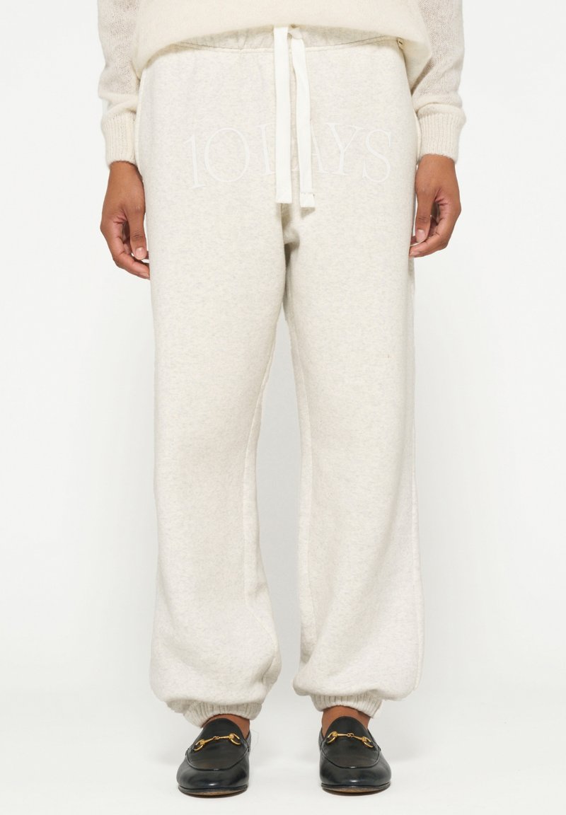 Lichtgrijze sweatpants met elastische boorden en een trekkoord in de taille, met de tekst "10 DAGEN" in een muted tint aan de voorkant.