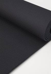 Black textured yoga mat rolled partially open, featuring a non-slip surface with a diamond pattern and smooth edges.
