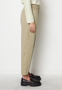 Beige elastische taillebandbroeken met een taps toelopende pijp, gemaakt van glad katoen, gecombineerd met zwarte loafers met een chunky zool.
