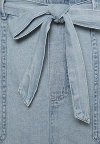 Světlomodré džínové šaty s páskem vázaným v pase, měkkou texturou a viditelnými ševními detaily. Součástí jsou boční kapsy.