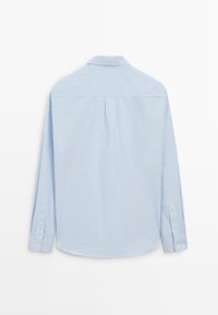 Lyseblå langærmet skjorte med lodrette hvide striber, knappet krave og manchetter med to knapper. Glat stof med en afslappet pasform.