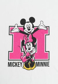Maglietta grafica caratterizzata da uno sfondo bianco con una lettera "M" di colore rosa. Rappresenta Topolino in alto e Minni in basso, entrambi in contorno nero.