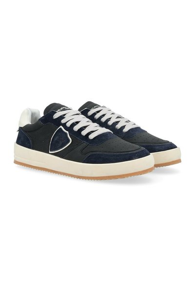 Sneaker blu navy realizzati con una combinazione di materiali in pelle e suede, dotati di lacci bianchi, dettagli perforati e una suola in gomma color beige.