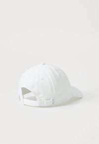White baseball cap featuring a rounded crown, adjustable strap at the back, and stitched details with a subtle logo accent.