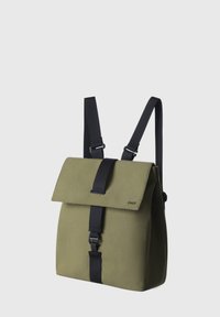 Sac à dos vert avec un rabat pliable, fermetures à sangle noires et bretelles réglables. Texture lisse et design minimaliste.