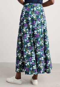 Floral maxi skirt in navy, featuring white, purple, and green flowers. Lightweight fabric with pleats, shown with white sneakers.